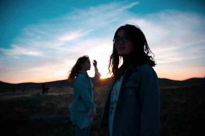 women standing on mountain during sunset